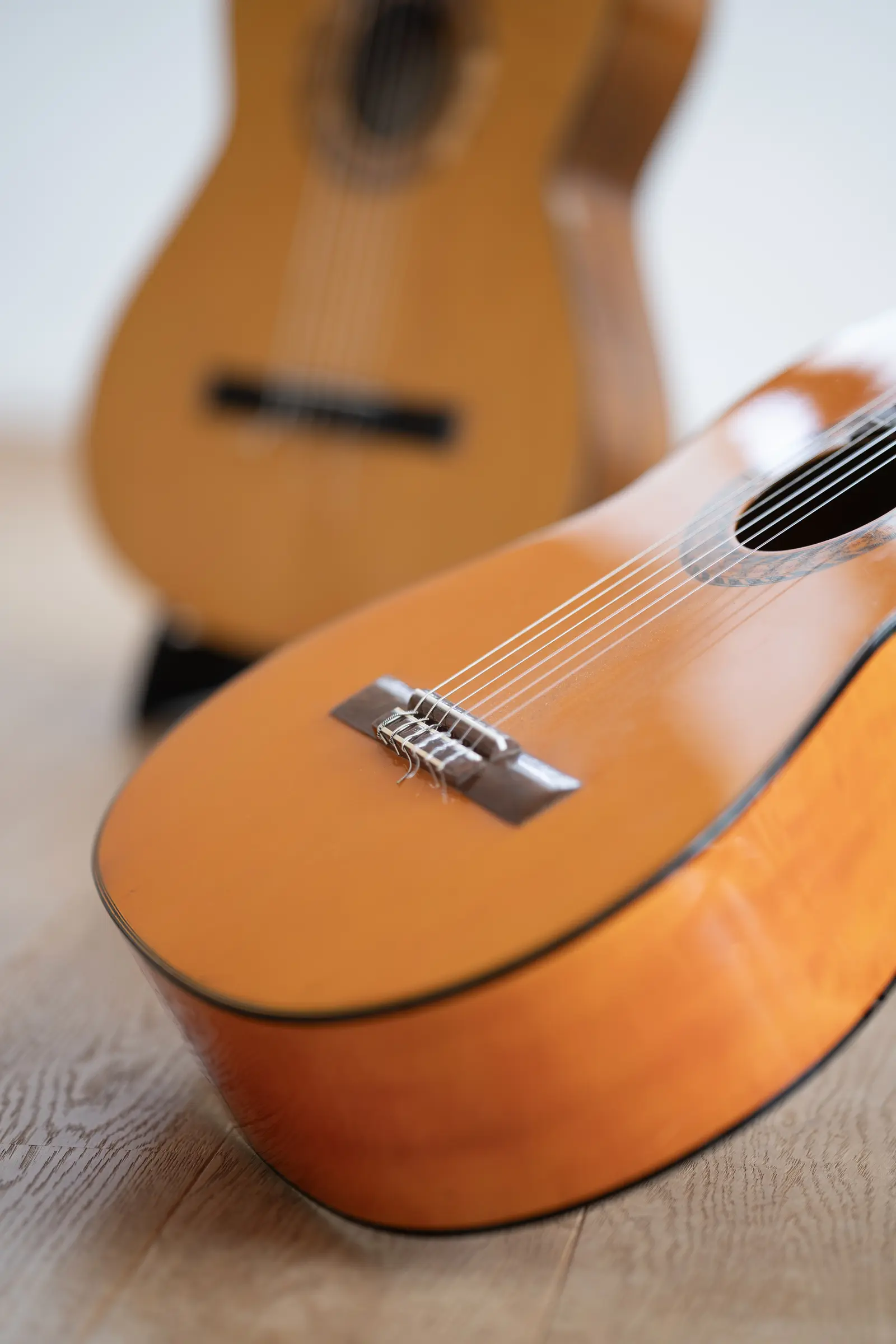 Detailaufnahme einer klassischen Gitarre, die auf dem hellen Holzboden ruht