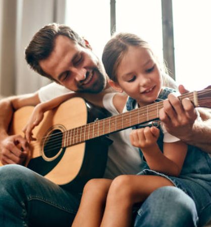 Eltern- und Kinderhände spielen gemeinsam auf einer Akustikgitarre