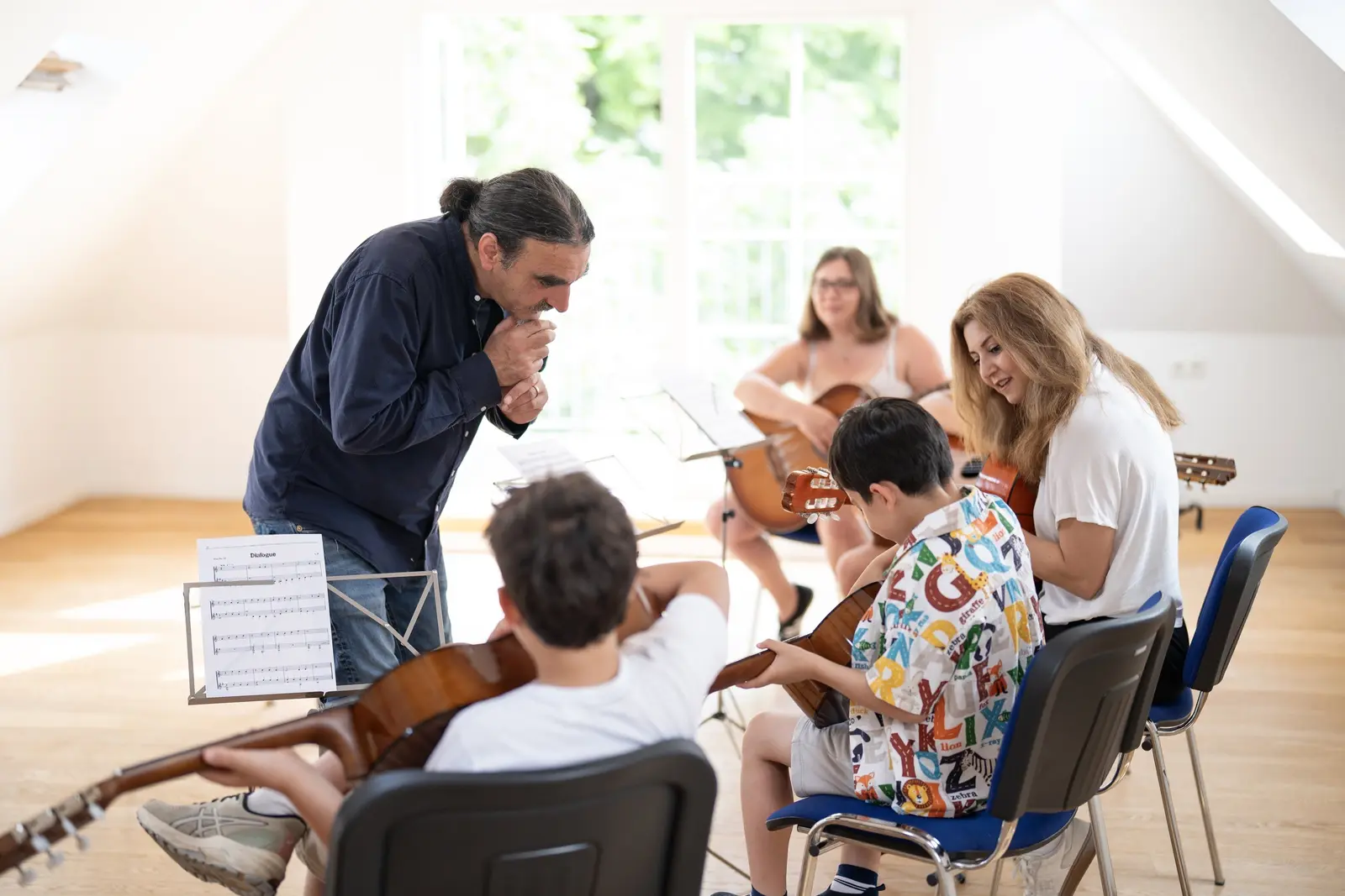 Gemeinsamer Gitarrenunterricht in entspannter Atmosphäre mit Lehrer und Schülern