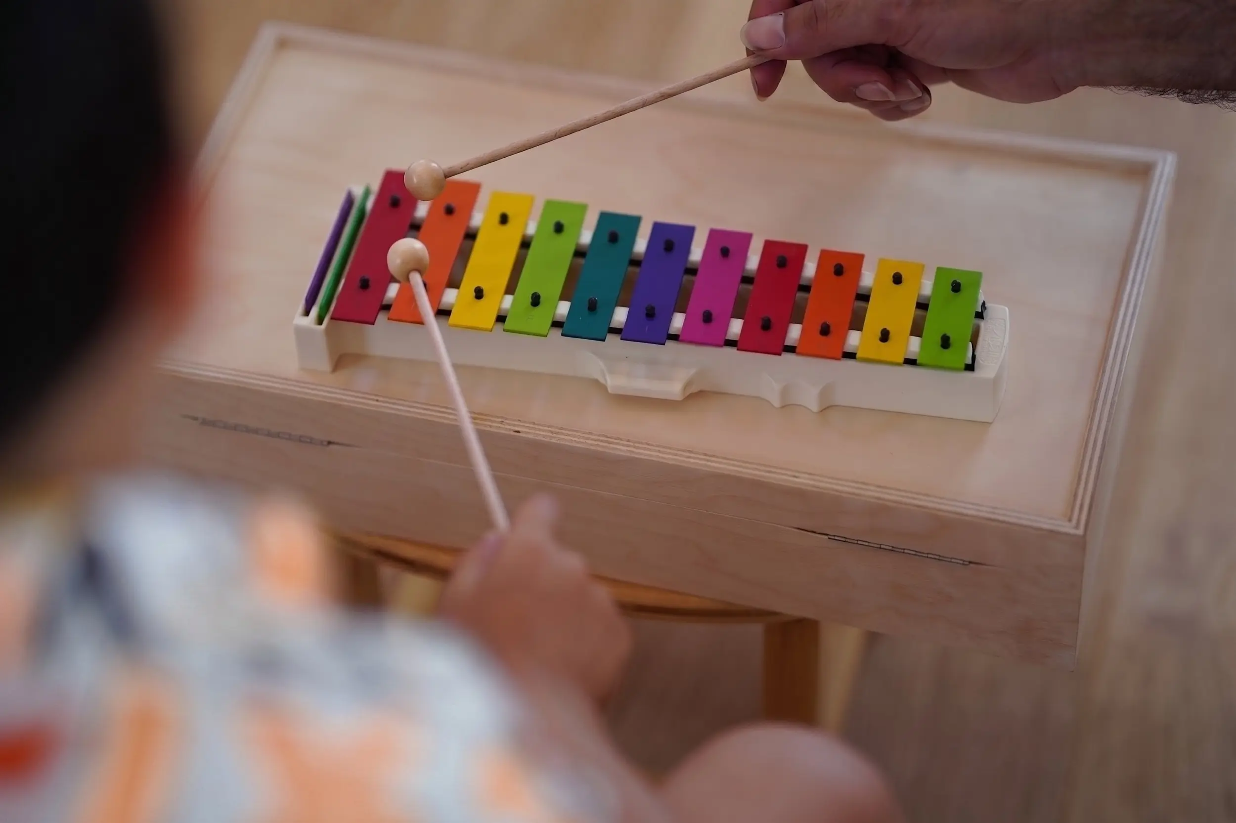 Ein Kind spielt auf einem bunten Xylophon aus Holz in der musikalischen Früherziehung